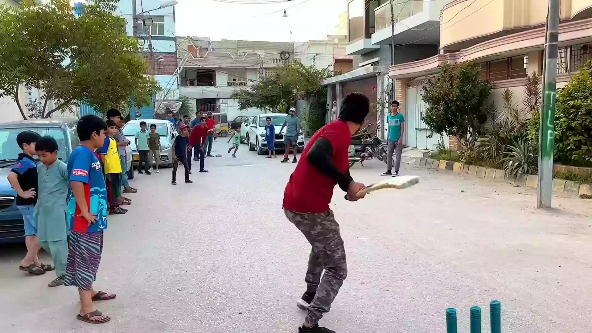 A batsman hitting a shot in desi street cricket match.